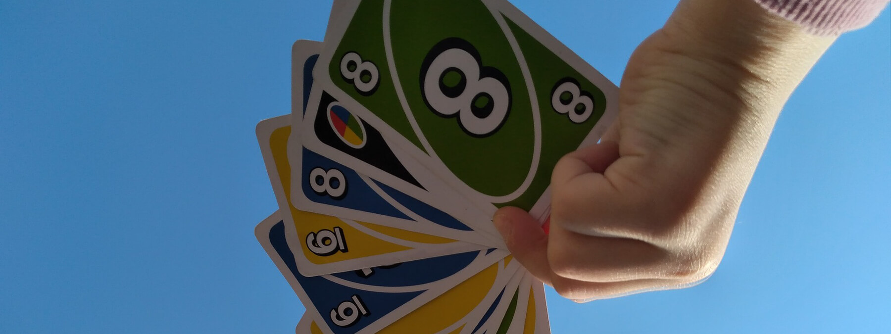 A hand holding a set of uno cards in the air